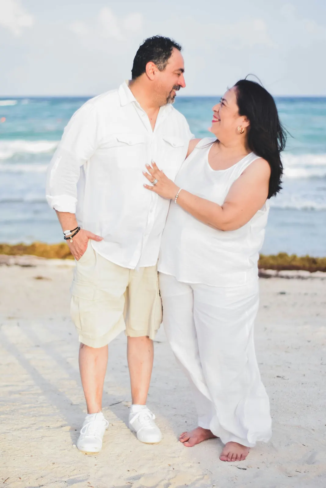 Middle-aged couple embracing and smiling on the beach
