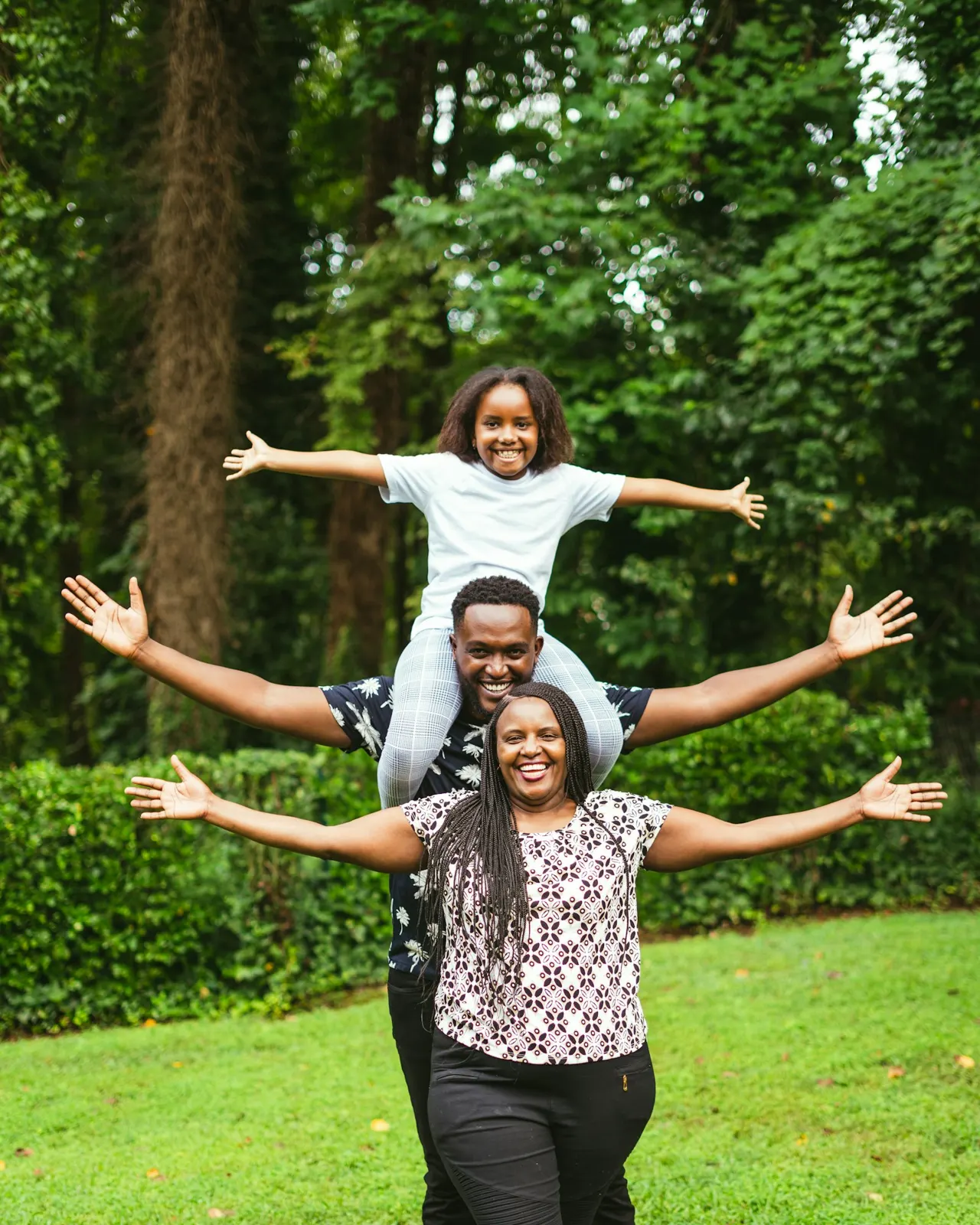 Joyful family stretching their arms out together in a green park